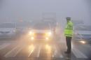 A traffic police works among heavy smog during a polluted day in Bozhou
