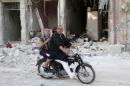A man with a leg cast rides a motorcycle though a damaged site after what activists said was an airstrike by forces loyal to Syria's President Bashar al-Assad in Old Aleppo, Syria