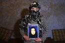 Fatima, 13, holds a picture of her mother Narges Rezaeimomenabad, suspected of killing a U.S. contractor at a police headquarters, at her home in Kabul