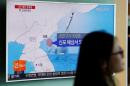 A passenger walks past a TV screen at a railway station in Seoul, South Korea, broadcasting a news report on North Korea's submarine-launched ballistic missile