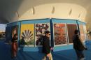 Onlookers walk by a collection of Olympic posters made by 12 Brazilian artists and a Colombian, on display at the Museum of Tomorrow in Rio de Janeiro, Brazil, Tuesday, July 12, 2016. Olympics organizers broke with tradition and unveiled a collection of 13 official Olympics posters, not the one single poster, typical in most games. (AP Photo Silvia Izquierdo)