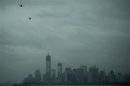 Helicopters fly over the skyline of lower Manhattan as it sits in darkness after a preventive power outage caused by Hurricane Sandy in New York