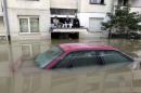 Men sit on a car porch during heavy floods in Bosanski Samac
