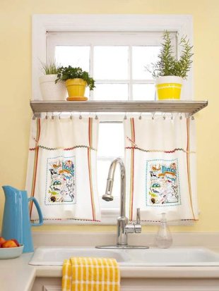 Using two kitschy tea towels clip drapery hooks to the top edge of a