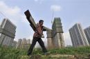 A garbage collector walks past residential and office buildings in construction, in Hefei