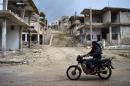 A Syrian man rides a motorbike past destroyed buildings in rebel-held town of Talbiseh on the northern outskirts of Homs on March 15, 2016