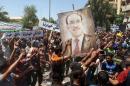 Iraqis hold a giant portrait of Iraq's Prime Minister Nuri al-Maliki during a demonstration to support him on August 11, 2014 in Baghdad's central Saadoun Street