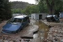 FILE - In this Sept. 13, 2013 file photo, cars lay mired in mud deposited by floods in Lyons, Colo. Little more than a year after Colorado Gov. John Hickenlooper assured the world his wildfire-ravaged state was still 