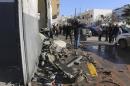 Civilians and security personnel stand at the scene of an explosion at a police station in the Libyan capital Tripoli