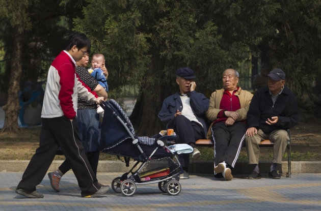 FILE - In this April 28, 2011 file photo, elderly men rest on a bench as a family with their new born baby walk past at a park in Beijing, China. Visit your parents. That's an order. So says China, whose national legislature on Friday, Dec. 28, 2012 amended its law on the elderly to require that adult children visit their aged parents "often" - or risk being sued by them. (AP Photo/Alexander F. Yuan, File)