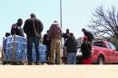 In this image made from video, volunteers from the United Auto Workers-Ford and other volunteers unload cases of water outside Sampson-Webber Leadership Academy in Detroit on Thursday, April 14, 2016. The academy is one of 19 schools in Detroit's school district that were found to have elevated levels of lead or copper in their water. (AP Photo/Mike Householder)