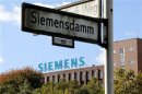A street sign is pictured in front of a factory with the logo of Siemens AG company in Berlin