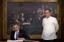 FILE - In this Monday, April 28, 2014 file photo, U.S. President Barack Obama signs a guestbook as Philippine President Benigno Aquino III looks on at the Malacanang Palace in Manila. A new defense pact that will allow thousands of U.S. troops to be temporarily based in Philippines for the first time in more than 20 years signals closer cooperation in the allies' hot-and-cold relationship that has been shaped over the decades by war, terrorism and now, jitters over China's rise. The 10-year agreement, signed Monday as Obama arrived in Manila, was considered the centerpiece of his four-nation Asian trip, which he used to reassure allies like Japan and the Philippines of American military backing as they wrangle with China in increasingly tense territorial disputes. (AP Photo/Carolyn Kaster, File)