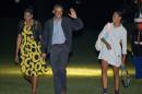 President Barack Obama, center, and first lady Michelle Obama, left, walk with their daughter Malia, right, across the South Lawn of the White House in Washington, Sunday, Aug. 24, 2014, following their arrival on Marine One helicopter. Obama returned to Washington after spending two weeks with his family on the island of Martha's Vineyard. (AP Photo/Pablo Martinez Monsivais)
