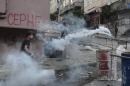 Left-wing protesters try to avoid tear gas and water used by police to disperse them, in Istanbul, Sunday, July 26, 2015, during clashes between police and people protesting against Turkey's operation against Kurdish militants. The graffiti on the background reads in Turkish 'Front'. Turkey has bombed Islamic State positions near the Turkish border in Syria, also targeting Kurdish rebels in Iraq and carried out widespread police operations against suspected Kurdish and IS militants and other outlawed groups inside Turkey. (AP Photo/Cagdas Erdogan) TURKEY OUT