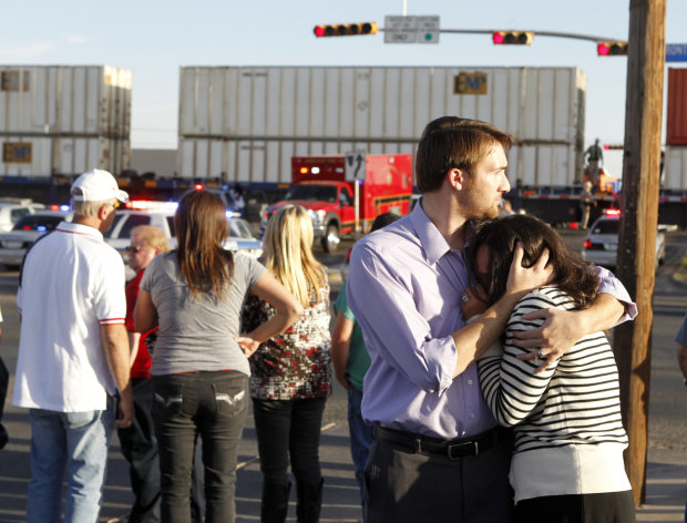 Bystanders react as emergency personnel work the scene where a trailer carrying wounded veterans in a parade was struck by a train in Midland, Texas, Thursday, Nov. 15, 2012. "Show of Support" president and founder Terry Johnson says there are "multiple injuries" after a Union Pacific train slammed into the trailer, killing at least four people and injuring 17 others. (AP Photo/Reporter-Telegram, James Durbin)