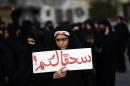 A Bahraini woman takes part in a protest in the village of Jidhafs, west of Manama, against the execution of prominent Shiite Muslim cleric Nimr al-Nimr by Saudi authorities, on January 2, 2016. The writing in Arabic reads "Damn you"