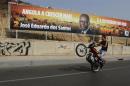 A motorcyclist rides past an election poster of the ruling MPLA party with the picture of President Jose Eduardo dos Santos in the capital Luanda