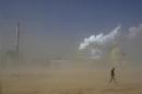 File photo of a man walking past a coal plant amidst a dust storm in Lingwu, Ningxia Hui Autonomous Region