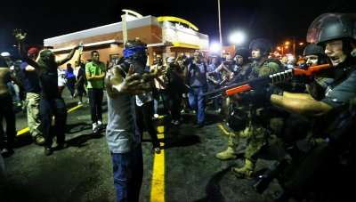 Police officers move in to arrest protesters as they push and clear crowds out of the West Florissant Avenue area in Ferguson, Mo. early Wednesday, Aug. 20, 2014. On Aug. 9, 2014, a white police officer fatally shot Michael Brown, an unarmed black 18-year old, in the St. Louis suburb. (AP Photo/Atlanta Journal-Constitution, Curtis Compton)