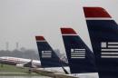An American Airlines jet takes off while U.S. Airways jets are lined up at Reagan National Airport in Washington