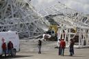 People stand near a metal structure that buckled on part of the Itaquerao Stadium in Sao Paulo, Brazil, Wednesday, Nov. 27, 2013. Part of the stadium that will host the 2014 World Cup opener in Brazil collapsed on Wednesday, causing significant damage and killing at least two people, authorities said. (AP Photo/Nelson Antoine)