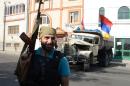 An armed man stands in front of a vehicle bearing Armenian flags in Yerevan on July 23, 2016