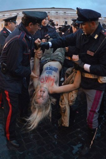 Une militante du groupe Femen évacuée par la police près de la place Saint-Pierre, à Rome, le 12 mars 2013