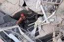 A rescuer searches for survivors through a huge pile of rubble, all that was left of a 10-story apartment building destroyed by a gas explosion Tuesday, in Rosario, Argentina, Wednesday, Aug. 7, 2013. Firefighters were mostly working by hand, using a sensitive listening device and body-sniffing dogs to try to reach victims thought to be trapped two stories underground. The Tuesday blast killed 10 people, injured dozens and left 13 unaccounted for. (AP Photo/Alejandro Rio)