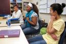 In this Jan. 26, 2016 photo, Nakafu Kahasha, center, describes her short story about her journey from Congo to Tanzania to Fargo, N.D., nearly six years ago, while Nepal natives Anju Tamang, left, and Anju Gurung listen during a break in their English language learners class at Fargo South High School. The three students are among others in the class who wrote stories about their resettlement for a self-published book that has been popular in the school. (AP Photo/Dave Kolpack)