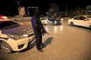 A member of the Special Deterrence Force stands near a car at a checkpoint in Tripoli, Libya
