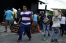 People carry goods taken from a food wholesaler after it was broken into, in La Fria