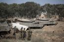 Israeli soldiers stand next to their tanks in an army deployment area near the border with the Gaza Strip on July 6, 2014 after more than 135 rockets hit Israel over the past 24 days