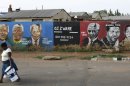 FILE - In this Dec. 11, 2012 file photo, a woman walks past a mural depicting portraits of former South African President Nelson Mandela in Soweto, South Africa. The chipped street mural depicts stations in the life of Mandela each matched by a portrait of the global icon as he advanced from robust youth to old age. Now this infirm giant of history faces a struggle with mortality, it's duration unknown but its outcome certain. (AP Photo/Themba Hadebe, File)