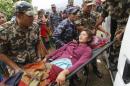 Sita Karka, suffering two broken legs from Saturday's massive earthquake, is assisted into an ambulance by Nepalese soldiers and police after arriving by helicopter from the heavily-damaged Ranachour village at a landing zone in the town of Gorkha, Nepal, Tuesday, April 28, 2015. Helicopters crisscrossed the skies above the high mountains of Gorkha district on Tuesday near the epicenter of the weekend earthquake, ferrying the injured to clinics, and taking emergency supplies back to remote villages devastated by the disaster. (AP Photo/Wally Santana)