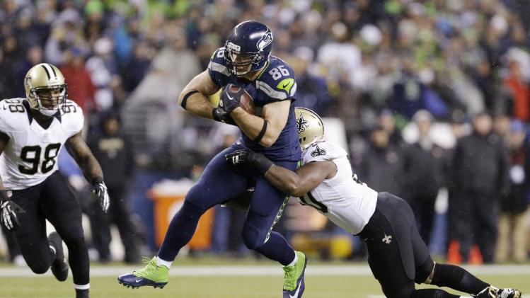 Seattle Seahawks' Zach Miller (86) is brought down by New Orleans Saints' Curtis Lofton as Parys Haralson (98) moves in in the first half of an NFL football game, Monday, Dec. 2, 2013, in Seattle
