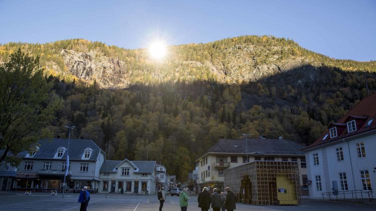 People gather in front of the town hall, where sunlight is reflected by giant mirrors erected on the mountainside, in Rjukan