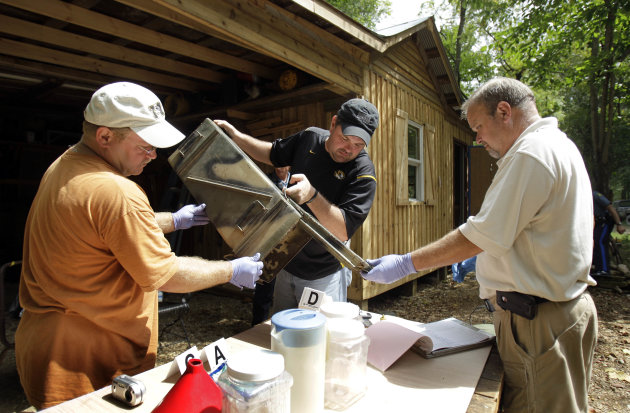 FILE - In this Sept. 2, 2010 file photo, Franklin County Detective Jason Grellner, center, sorts through evidence with Detective Darryl Balleydier, left, and reserve Officer Mark Holguin during a raid of a suspected meth house in Gerald, Mo. Methamphetamine lab seizures are on the rise in the nation's cities and suburbs, raising new concerns about a lethal drug that has long been the scourge of rural America. (AP Photo/Jeff Roberson, File)