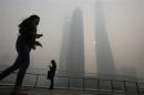 Residents wearing face masks use their mobile phones on a hazy day at the Pudong financial area in Shanghai