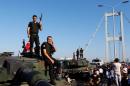 Policemen stand atop military armored vehicles after troops involved in the coup surrendered on the Bosphorus Bridge in Istanbul