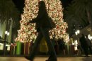 In this Thursday, Dec. 20, 2012, photo, a holiday shopper walks past a large Christmas tree at Fashion Island shopping center in Newport Beach, Calif. A last-minute surge in spending helped many major U.S. retailers report better-than-expected sales in December, a relief for stores that make up to 40 percent of annual revenue during the holiday period. (AP Photo/Chris Carlson)