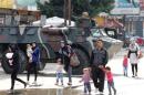 Civilians walk past a Lebanese army soldier patrolling on an armoured vehicles following clashes between Lebanese soldiers and Islamist gunmen in Tripoli