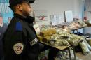 A French police officer standing near some of the cannabis, arms, ammunitions and bank notes seized by the Marseille police in one of the city's housing projects on January 15, 2016