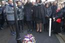Members of the family of late policewoman Clarissa Jean-Philippe, who died last year's January attacks, sing a gospel next to a wreath of flowers laid by French President Francois Hollande in Montrouge south of Paris, Saturday Jan. 9, 2016. Hollande is honoring 17 victims killed in Islamic extremist attacks on satirical newspaper Charlie Hebdo, a kosher market and police a year ago this week, unveiling plaques around Paris marking violence that ushered in a tumultuous year. (AP Photo/Michel Euler, Pool)