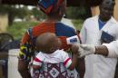 Health worker checks the temperature of a baby entering Mali from Guinea at the border in Kouremale