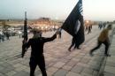ISIL fighter holds a flag and a weapon on a street in Mosul