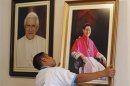 A worker hangs a portrait of Cardinal Luis Antonio Tagle of the Philippines next to a portrait of Pope Benedict XVI inside the Roman Catholic Archbishop headquarters in Manila