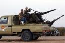 Members of a brigade loyal to Libya Dawn, an alliance of Islamist-backed militias, sit on a pick up truck mounted with a machine gun on March 15, 2015 in Libya's coastal city of Sirte