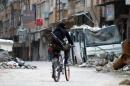 A rebel fighter carrying a weapon rides his bike in 2014 in a street in the northeastern city of Deir Ezzor