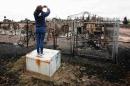 A woman takes photos of the burned remains of a house in the Abasand neighbourhood of Fort McMurray